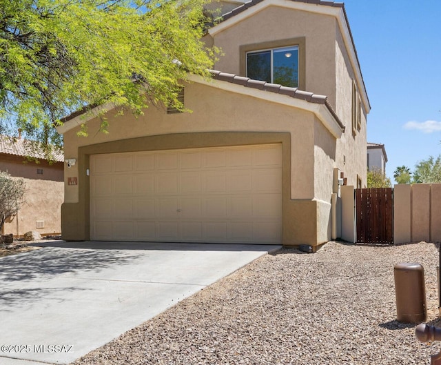view of front of home featuring a tiled roof, a garage, fence, concrete driveway, and stucco siding