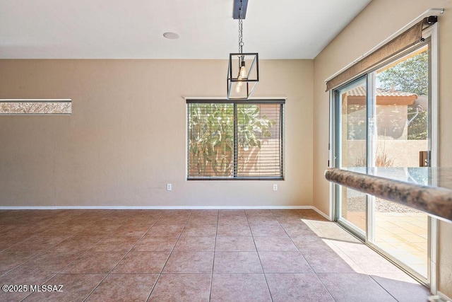 tiled empty room featuring baseboards