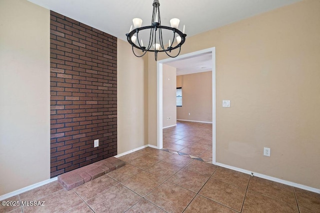 unfurnished room featuring brick wall, an inviting chandelier, baseboards, and tile patterned flooring