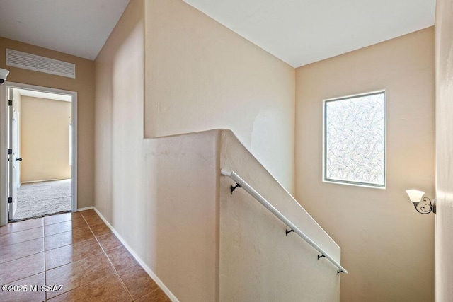 hall with baseboards, visible vents, and tile patterned flooring