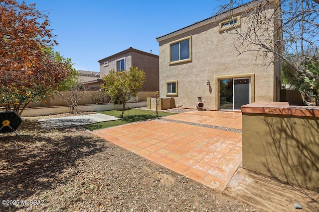 rear view of house featuring fence private yard, a patio area, and stucco siding