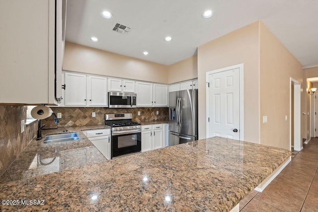kitchen with visible vents, decorative backsplash, stone countertops, a sink, and appliances with stainless steel finishes