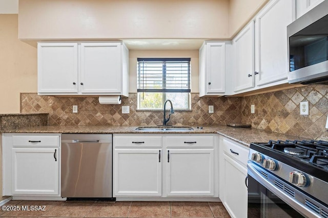 kitchen featuring decorative backsplash, light stone countertops, a sink, white cabinets, and stainless steel appliances