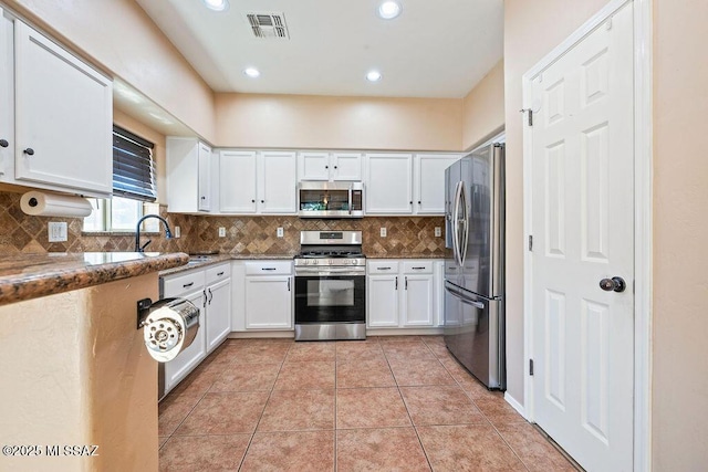 kitchen featuring white cabinets, a sink, stainless steel appliances, backsplash, and visible vents