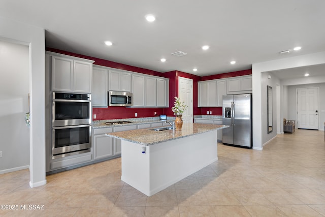 10337 S Pantano Knolls Dr, Vail, AZ 85641 - kitchen with appliances with stainless steel finishes, baseboards, a center island with sink, and light stone counters