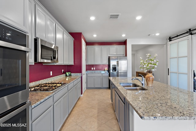 10337 S Pantano Knolls Dr, Vail, AZ 85641 - kitchen with a barn door, a sink, a kitchen island with sink, stainless steel appliances, and visible vents