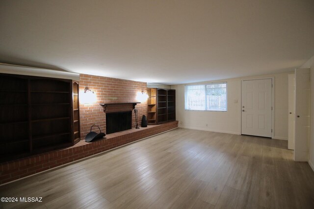 8133 E Colette Pl, Tucson, AZ 85710 - unfurnished living room with baseboards, built in features, a brick fireplace, and wood finished floors