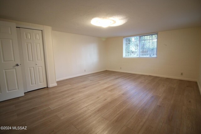 8133 E Colette Pl, Tucson, AZ 85710 - unfurnished bedroom featuring concrete block wall, baseboards, wood finished floors, and a closet