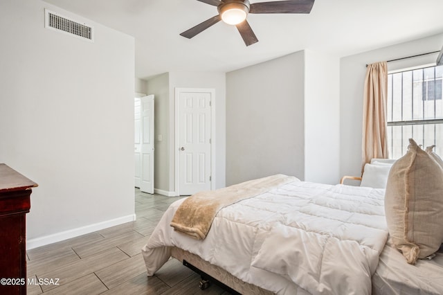 bedroom featuring visible vents, a ceiling fan, baseboards, and wood finished floors