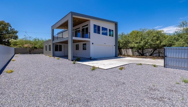4270 E Broadway Blvd, Tucson, AZ 85711 - back of house with a garage, a balcony, a fenced backyard, stucco siding, and concrete driveway