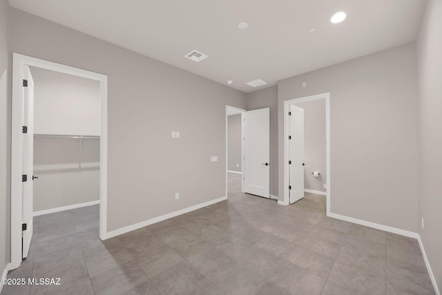 unfurnished bedroom featuring visible vents, baseboards, connected bathroom, a spacious closet, and recessed lighting