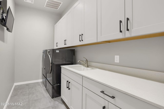 washroom featuring independent washer and dryer, cabinet space, a sink, baseboards, and visible vents