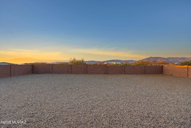 yard at dusk featuring a mountain view and a fenced backyard