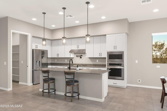 kitchen featuring visible vents, under cabinet range hood, a center island with sink, and stainless steel appliances