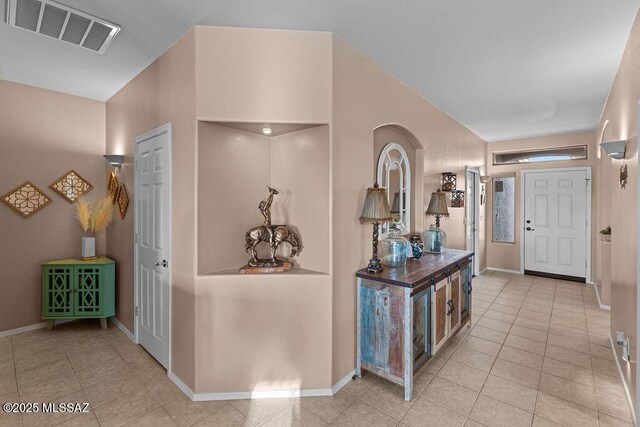 hallway with tile patterned floors, baseboards, and visible vents