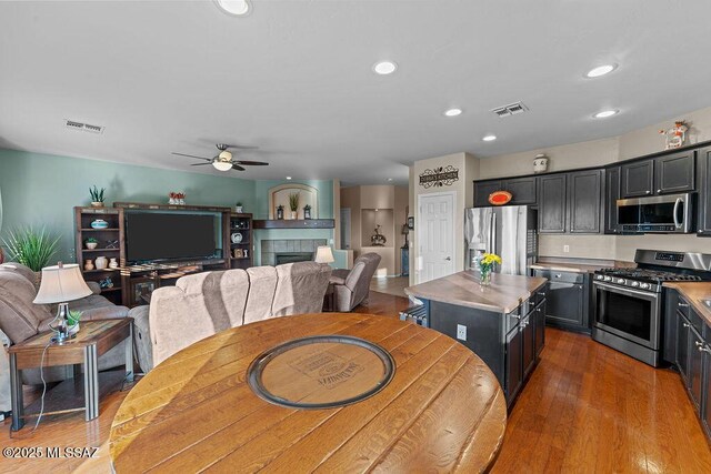 kitchen featuring a kitchen island, stainless steel appliances, visible vents, and a tile fireplace