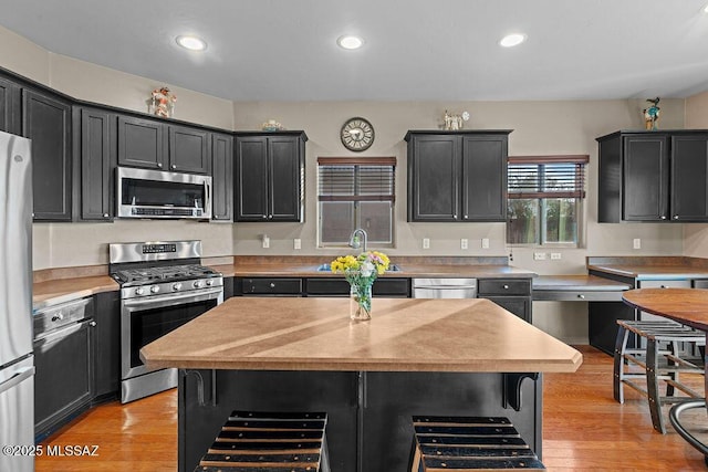 kitchen featuring a sink, light countertops, dark cabinetry, and stainless steel appliances