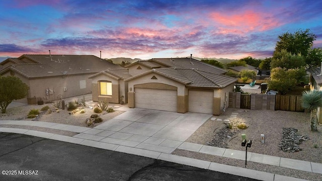view of front of house with a garage, fence, stucco siding, a tiled roof, and concrete driveway
