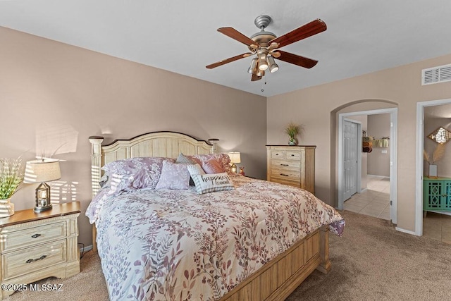 carpeted bedroom featuring visible vents, arched walkways, ceiling fan, and tile patterned floors
