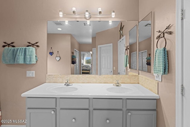 ensuite bathroom with double vanity, visible vents, a sink, and ensuite bath