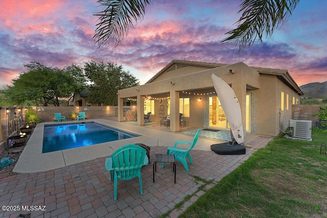 pool at dusk with a fenced in pool, central AC unit, a fenced backyard, and a patio area
