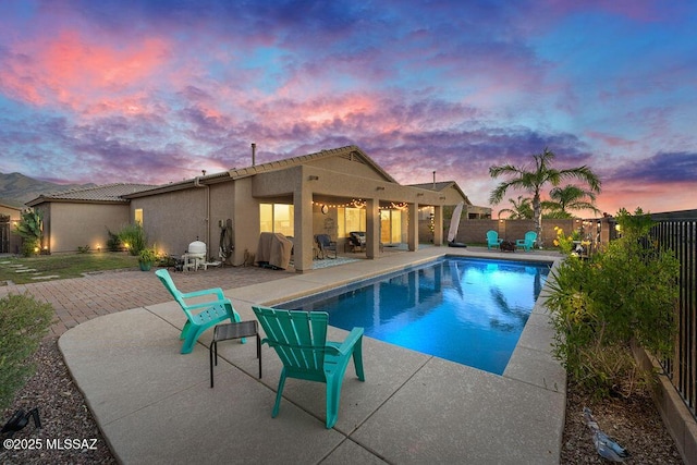 pool at dusk featuring a fenced in pool, a patio area, and fence