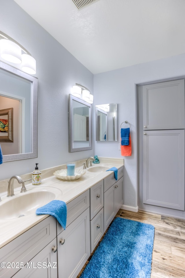 1707 W Sunridge Dr, Tucson, AZ 85704 - bathroom featuring double vanity, visible vents, a sink, and wood finished floors