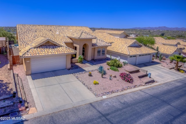 1707 W Sunridge Dr, Tucson, AZ 85704 - mediterranean / spanish-style home with an attached garage, stucco siding, a mountain view, concrete driveway, and a tiled roof