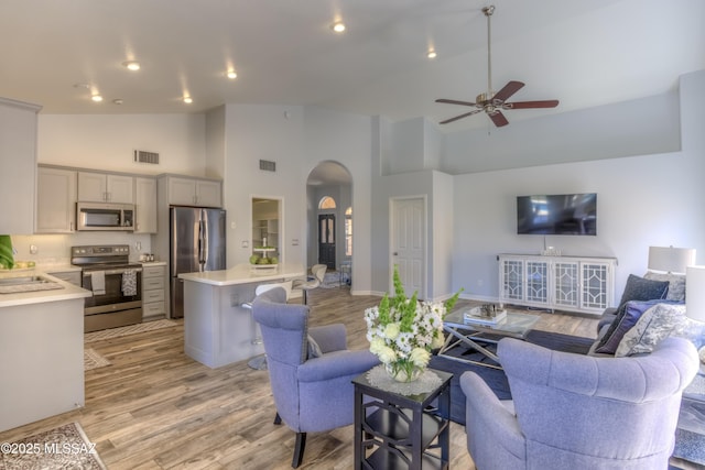 1707 W Sunridge Dr, Tucson, AZ 85704 - living room featuring ceiling fan, visible vents, arched walkways, high vaulted ceiling, and light wood finished floors