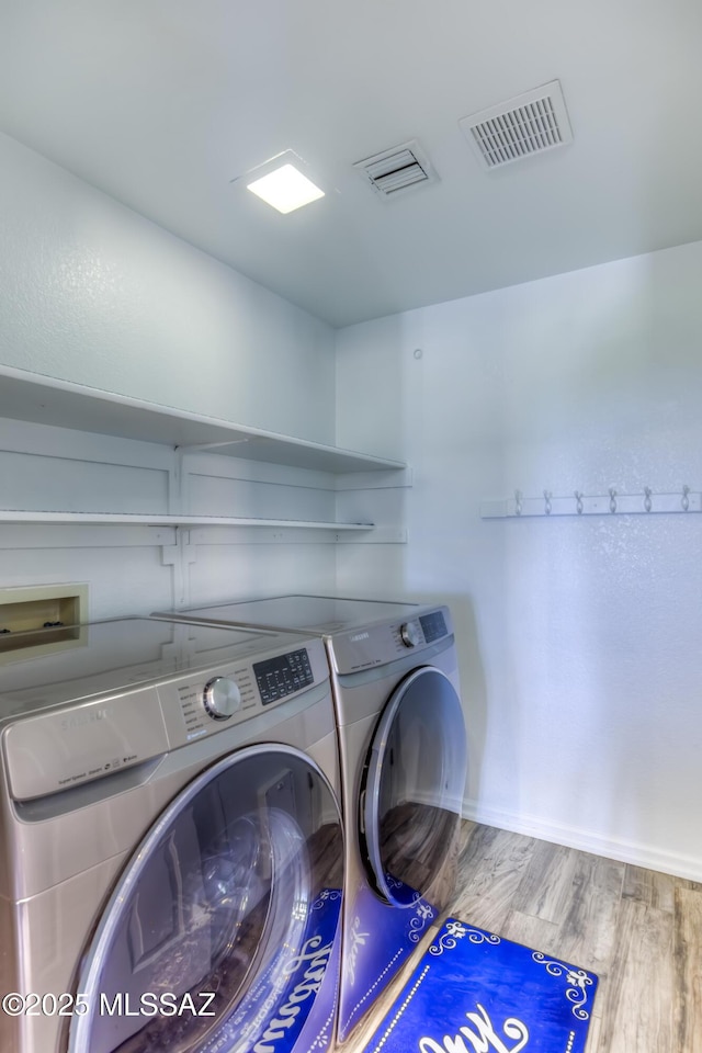 1707 W Sunridge Dr, Tucson, AZ 85704 - clothes washing area with laundry area, wood finished floors, visible vents, and washing machine and clothes dryer