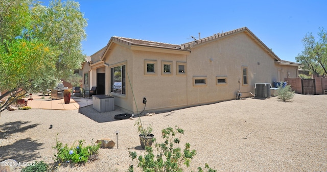 back of property with fence, stucco siding, a patio area, central air condition unit, and a tile roof