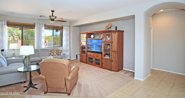 living room with a ceiling fan, arched walkways, and baseboards