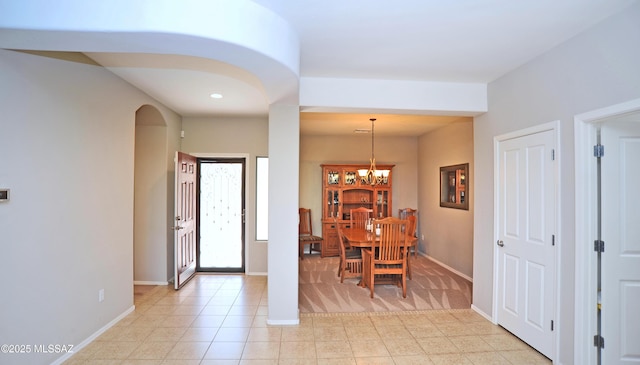 entrance foyer featuring baseboards, arched walkways, and a chandelier