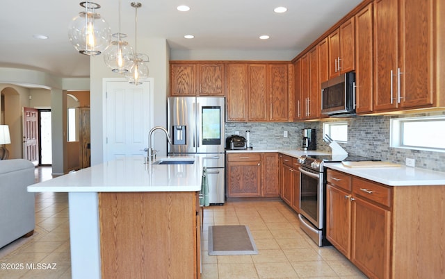kitchen featuring stainless steel appliances, arched walkways, decorative backsplash, and light tile patterned floors