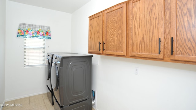 washroom with cabinet space, baseboards, light tile patterned floors, and washer and dryer