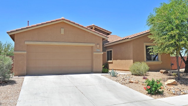 view of front facade with an attached garage, stucco siding, a tiled roof, and concrete driveway