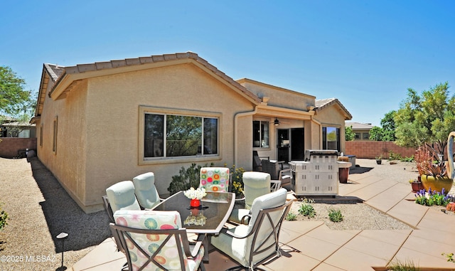 back of property featuring ceiling fan, outdoor dining area, a patio area, fence, and stucco siding