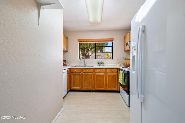 1525 N Bryant Ave, Tucson, AZ 85712 - kitchen featuring brown cabinets, a textured wall, a sink, white appliances, and light countertops