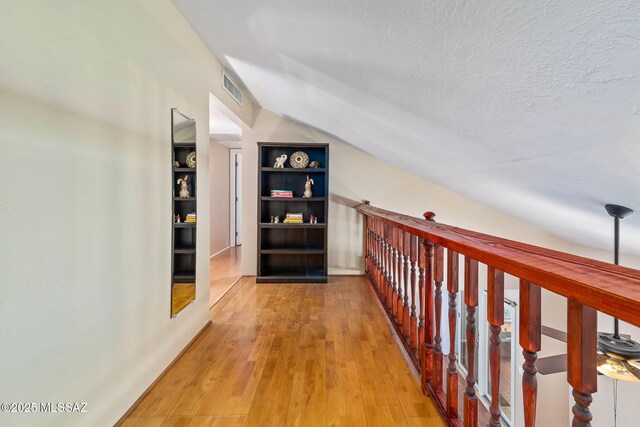1525 N Bryant Ave, Tucson, AZ 85712 - hall featuring a textured ceiling, visible vents, built in shelves, light wood finished floors, and lofted ceiling