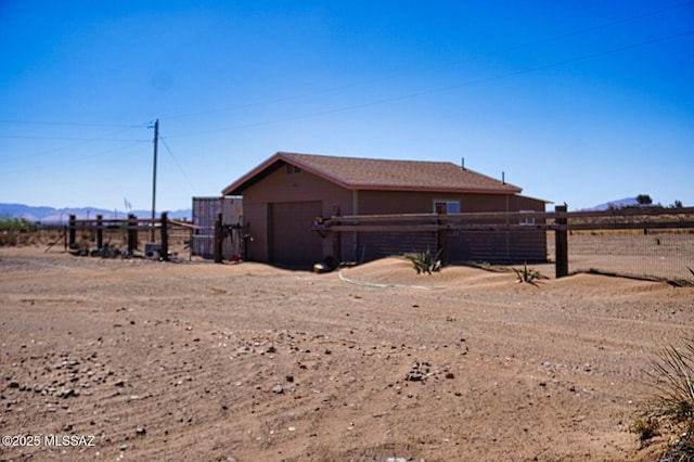 view of side of home featuring fence, an attached garage, and a mountain view