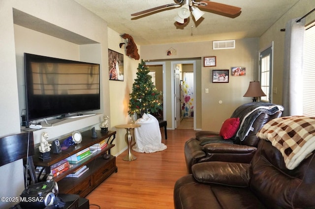 living room with ceiling fan, light wood-style flooring, and baseboards
