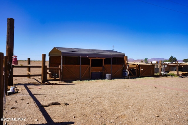 back of house with an exterior structure, a mountain view, and an outbuilding