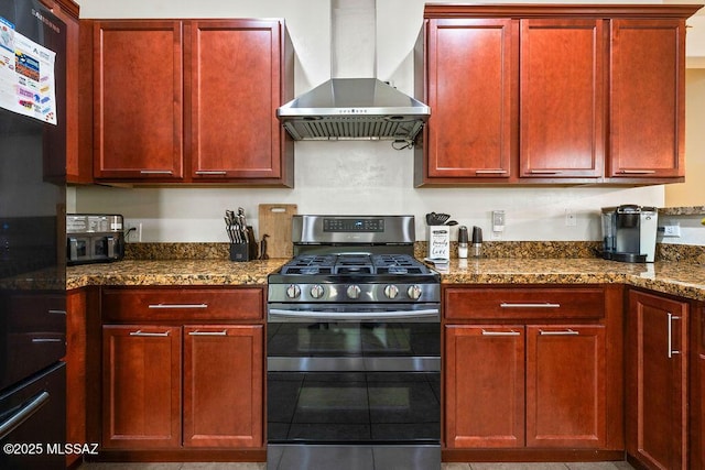 kitchen featuring double oven range, dark brown cabinets, dark stone countertops, black fridge, and wall chimney exhaust hood