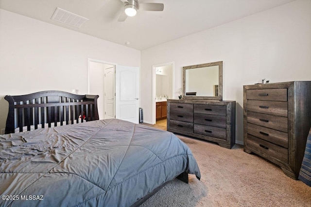 bedroom with visible vents, baseboards, light colored carpet, connected bathroom, and a ceiling fan