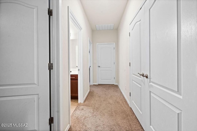 hall featuring baseboards, light colored carpet, and visible vents