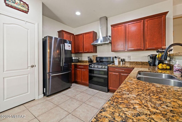 kitchen featuring freestanding refrigerator, gas range, wall chimney exhaust hood, a sink, and light tile patterned floors