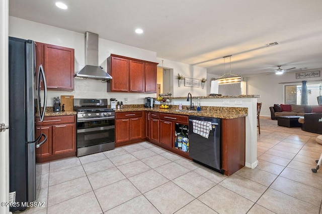 kitchen featuring appliances with stainless steel finishes, a sink, a peninsula, open floor plan, and wall chimney exhaust hood