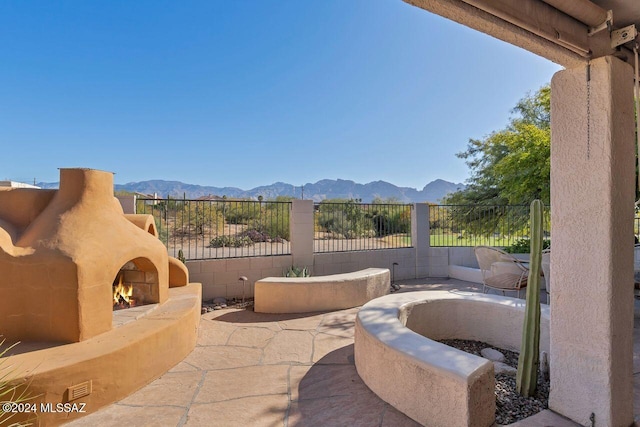 view of patio / terrace featuring a mountain view and a warm lit fireplace