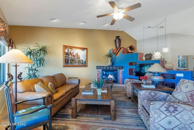living room with baseboards, a ceiling fan, vaulted ceiling, and a brick fireplace