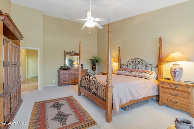 bedroom featuring a towering ceiling, ceiling fan, and light colored carpet